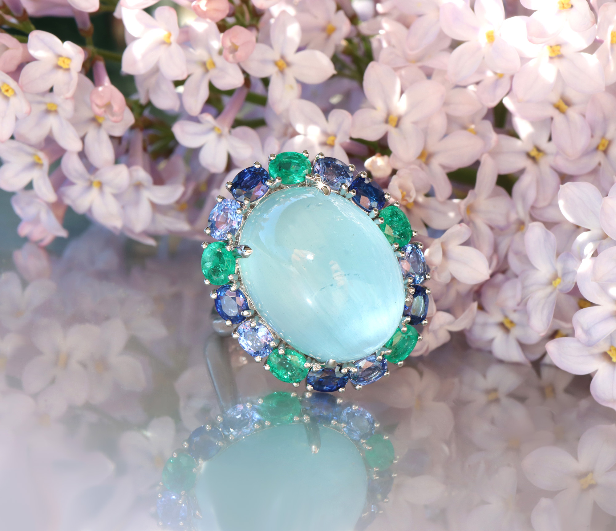 Milky Aquamarin-Ring mit Saphiren und Smaragden in Weißgold 750, umgeben von Lilienblüten.