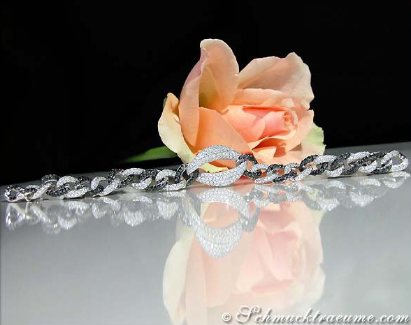 Schwarz-weißes Armband mit Diamanten auf glänzender Oberfläche, Rosenblüte im Hintergrund.