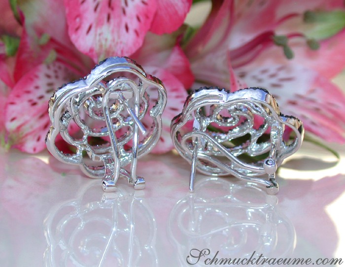 Silberne Rosenohrringe mit schwarzen Diamanten auf Blütenhintergrund