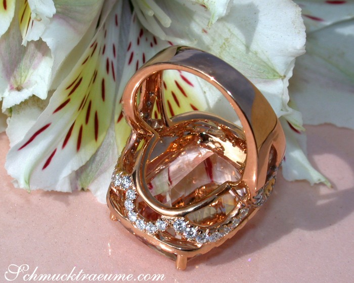 Goldener Morganit-Ring mit Brillanten auf Blütenhintergrund