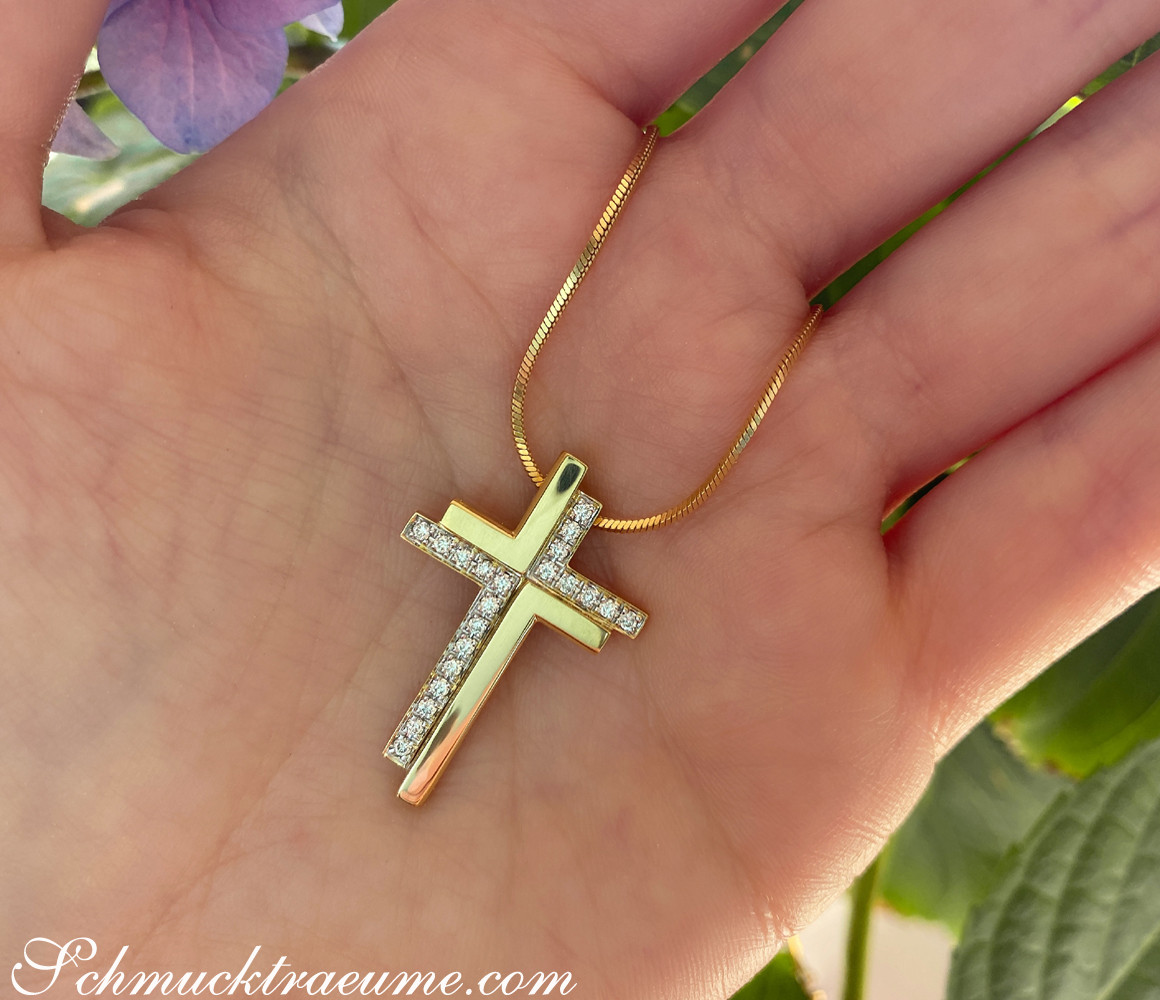 Goldener Kreuzanhänger mit Brillanten in Hand, Detailaufnahme