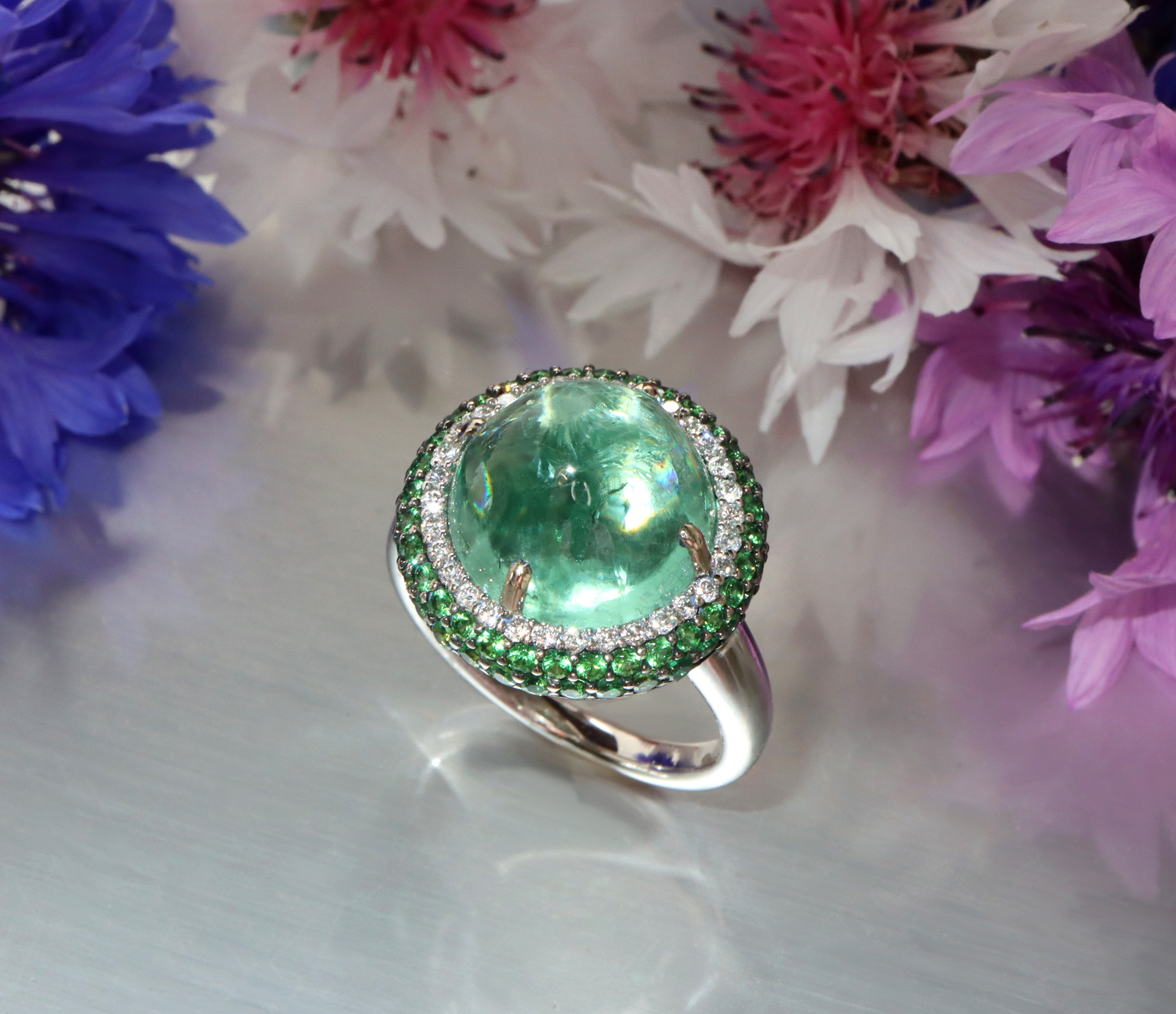 Minz-Turmalin-Ring mit Tsavorite und Brillanten, Weißgold 750, Blumenhintergrund.