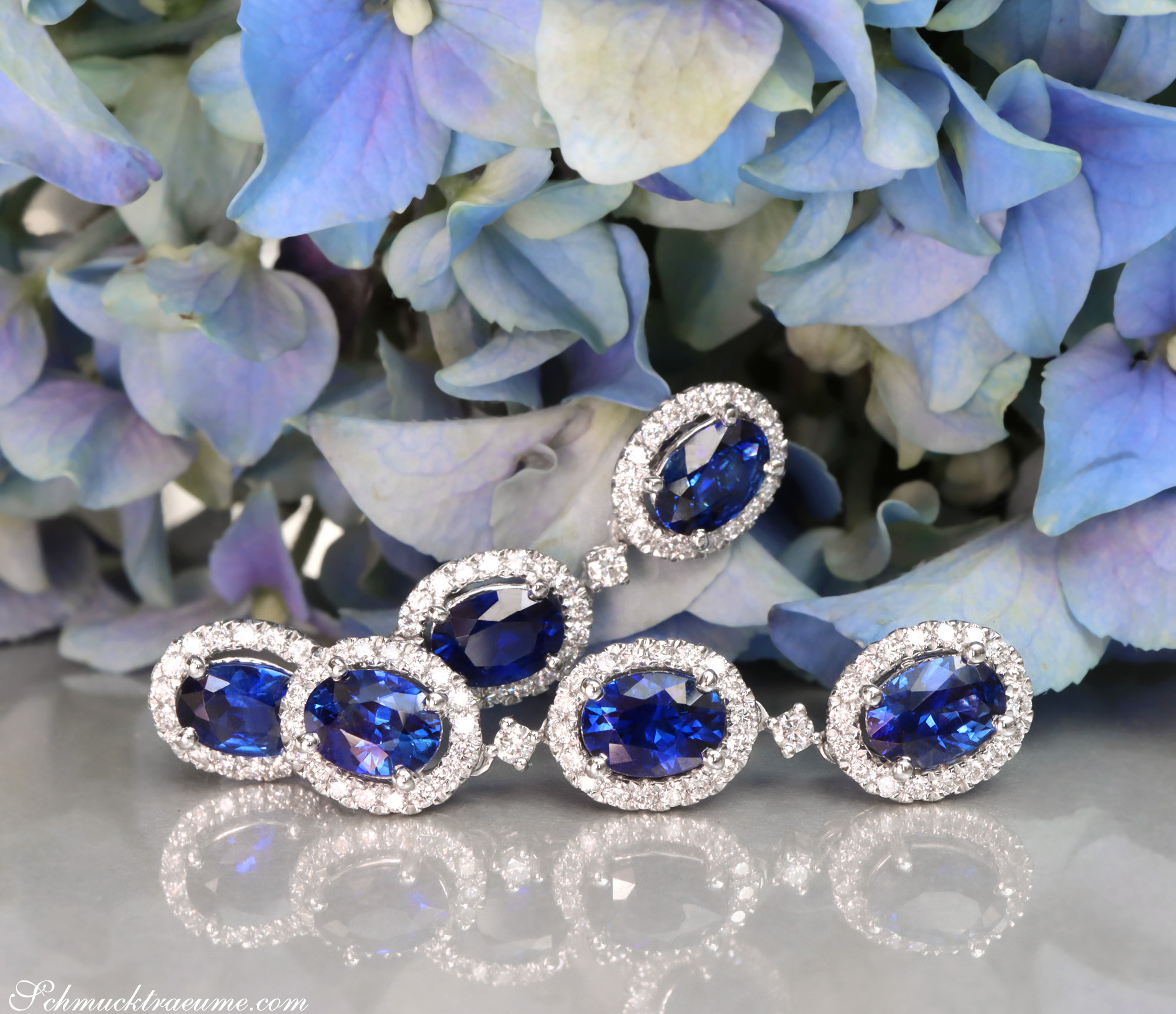 Ohrgehänge mit Saphiren und Brillanten auf Blumenhintergrund