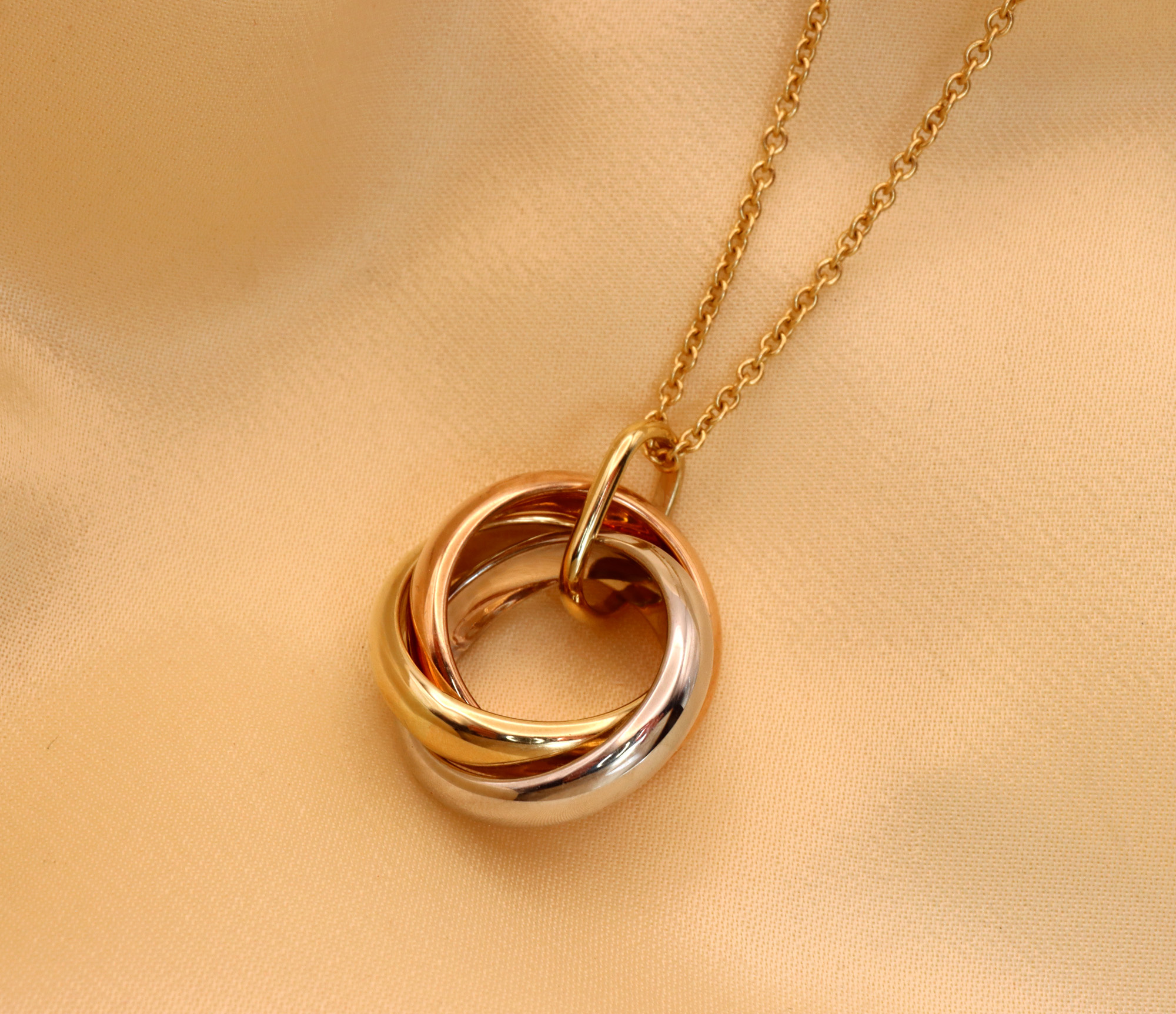 Gold Pur Tricolor Anhänger: Verschlungene Ringe aus Gelb-, Weiß- und Roségold 585 auf Kette.
