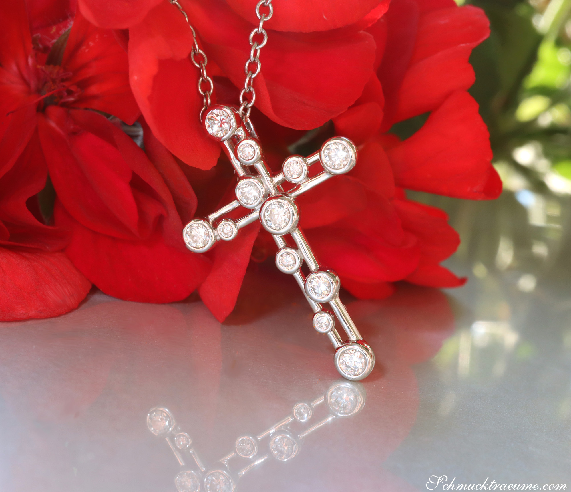 Kreuzanhänger aus Weißgold mit Brillanten, Detailaufnahme auf rotem Hintergrund