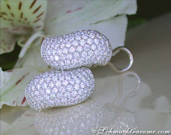 Detailansicht der gewellten Diamanten Ohrstecker, elegant geschwungen, glänzend, auf Blüte platziert.