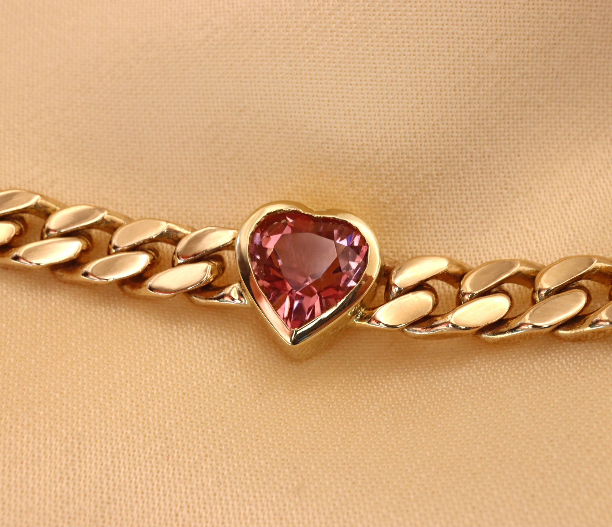Goldene Panzerarmband mit rosa Turmalin Herz, Detailaufnahme, elegant und glänzend.