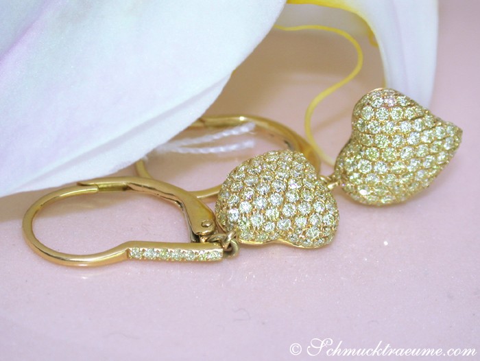 Goldene Herz-Ohrringe mit Diamantbesatz, Detailaufnahme von Ohrringhaken und Herzform.