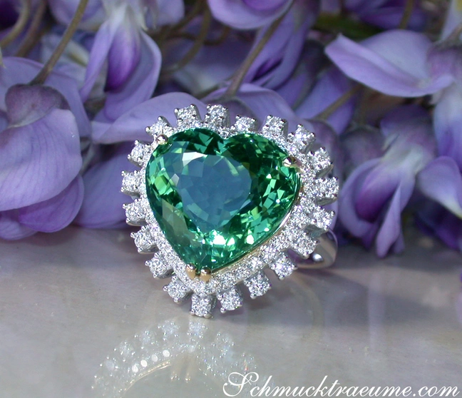 Herzform Turmalin-Ring mit Diamanten in Weißgold, Detailaufnahme auf lila Blüten. Herzform Turmalin-Ring mit Diamanten in Weißgold, Detailaufnahme auf lila Blüten.