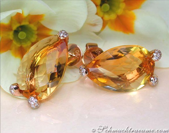 Goldene Citrin-Ohrstecker mit Diamanten, Detailaufnahme vor Blütenhintergrund