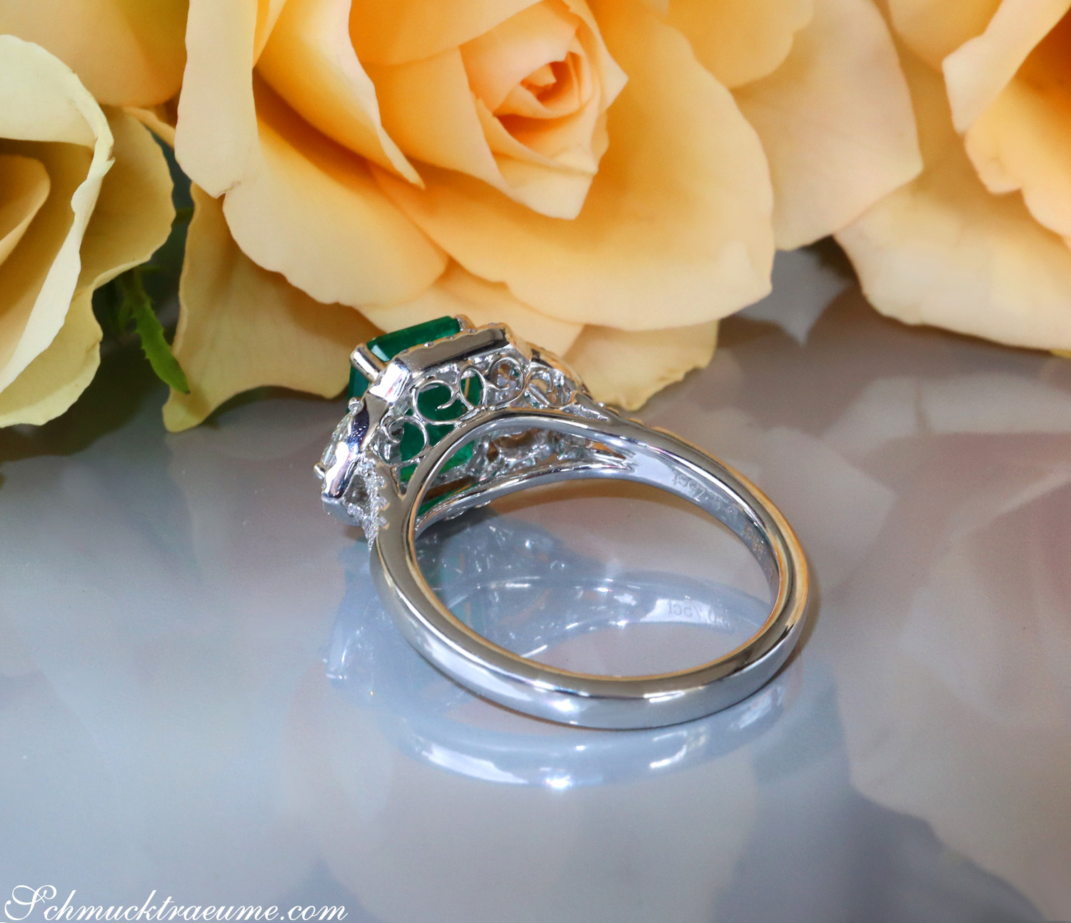 Klassischer Smaragd-Ring mit Diamant-Verzierungen und Rosen im Hintergrund