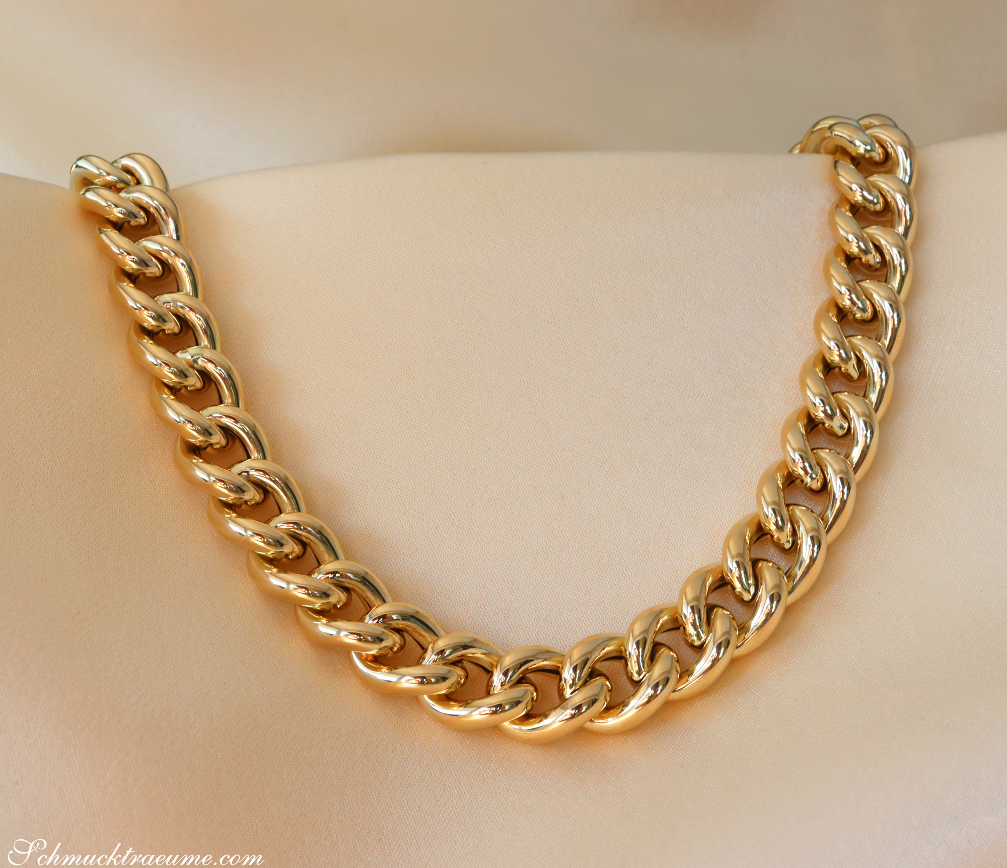 Goldene Panzerkette in Gelbgold 585, glänzend und luxuriös, auf cremefarbenem Hintergrund.