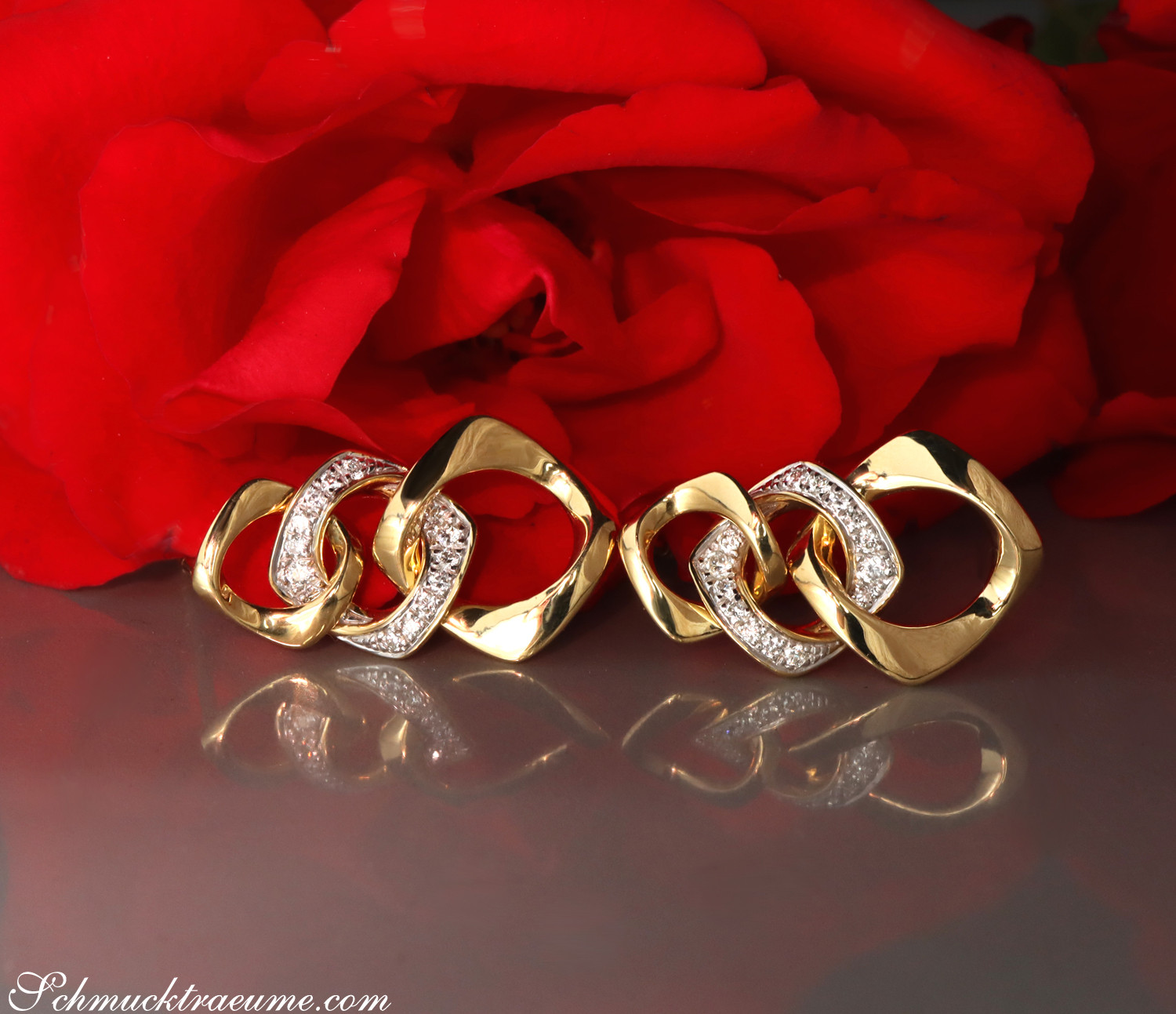 Klassische Goldohrringe mit Brillanten im Gliederdesign vor roter Rose