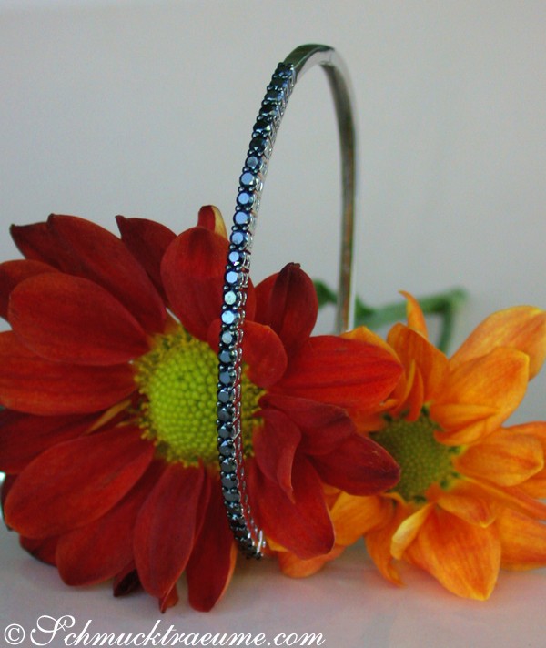 Detailansicht von Weißgold-Armreif mit schwarzen Diamanten, umgeben von leuchtenden Blumen