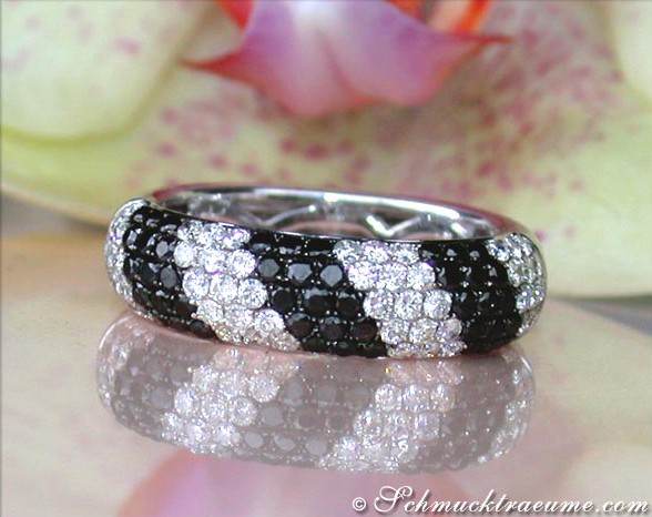 Weißgold-Ring mit schwarzen und weißen Diamanten, Detailaufnahme, Blume im Hintergrund