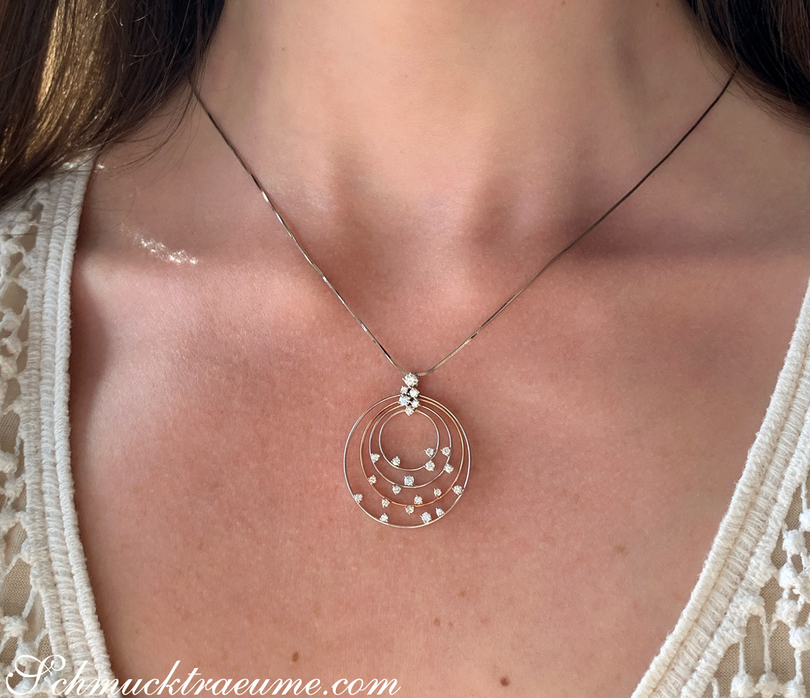 Kreisförmiger Anhänger mit funkelnden Brillanten auf Halskette, getragen.