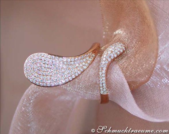 Geschwungener Roségold-Ring mit Brillanten, Detailaufnahme auf rosa Stoff, eleganter Chic