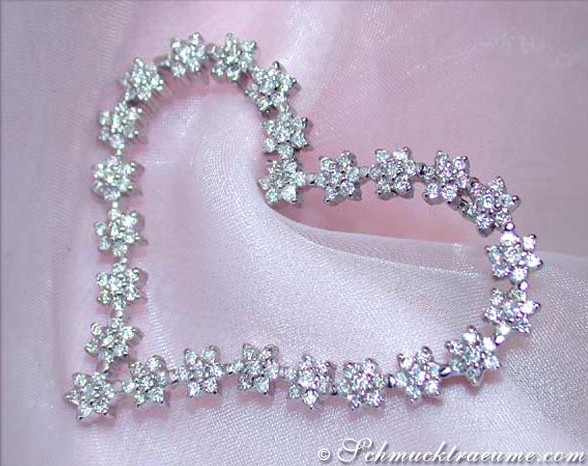 Herz-Anhänger aus Weißgold mit funkelnden Diamanten auf rosa Stoff.