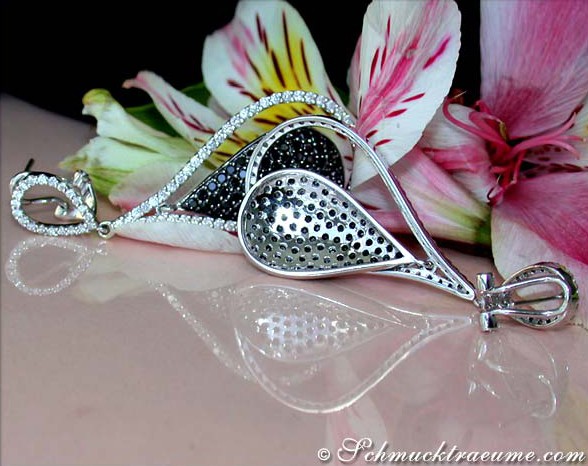 Schwarze und weiße Diamant-Ohrgehänge in Weißgold, Detailansicht mit Lilien im Hintergrund.