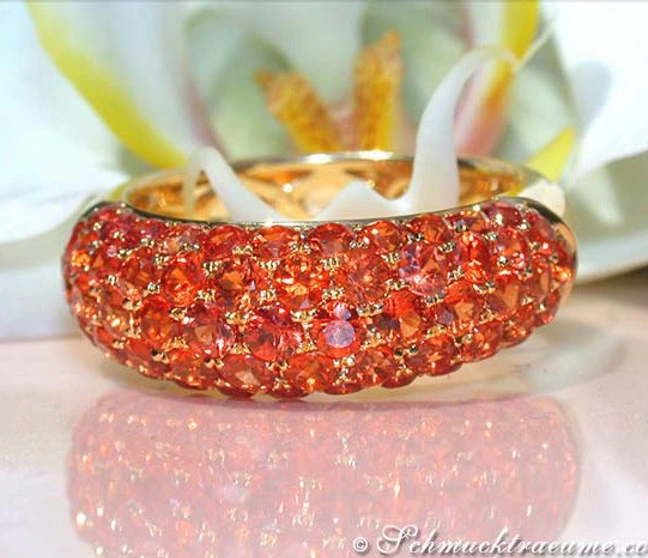 Goldener Pavé-Ring mit orangenen Saphiren auf glänzender Unterlage Goldener Pavé-Ring mit orangenen Saphiren auf glänzender Unterlage