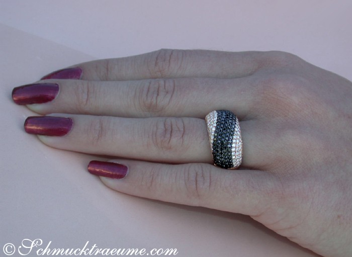 Schwarz-weißer Pavé-Ring mit Wellenmuster auf Hand mit lackierten Nägeln