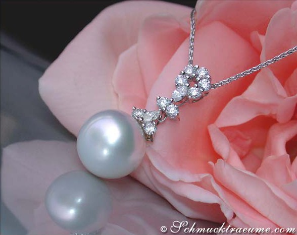 Detailaufnahme eines Südseeperlenanhängers mit Brillanten & Diamanten, präsentiert auf einer rosa Rose