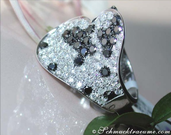 Herzform Ring mit schwarz-weißen Diamanten, detailreich verziert, auf weißem Hintergrund.