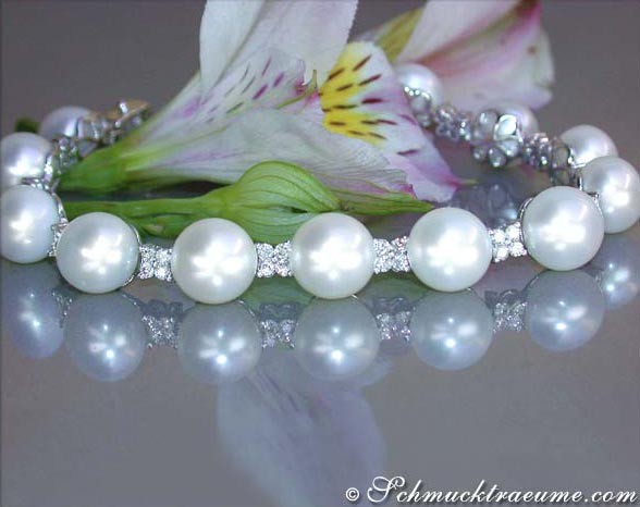 Perlenarmband mit Diamanten auf glänzender Oberfläche, Blume im Hintergrund