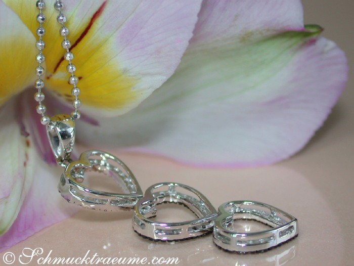 Herz-Anhänger aus Weißgold mit braunen, weißen & schwarzen Diamanten, Detailaufnahme, Blume im Hintergrund