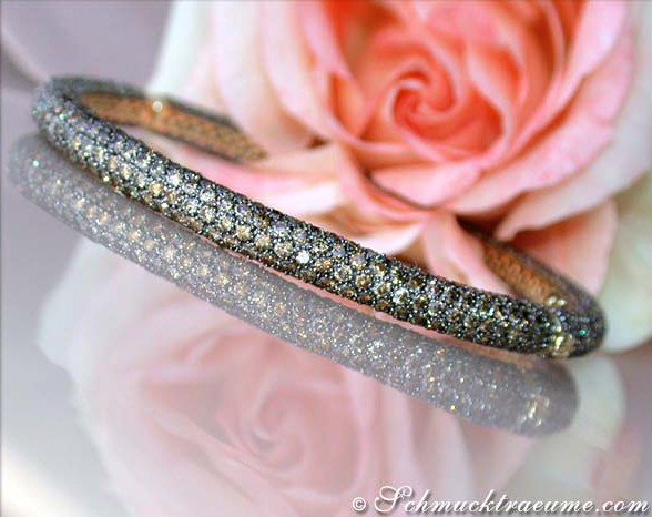 Glanzvolle Diamant-Armreife mit naturbraunen Steinen auf Rosenblüte.