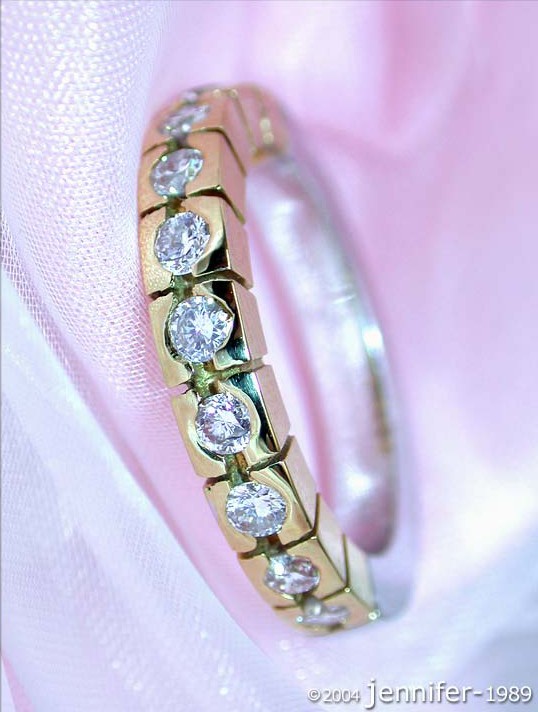 Gelbgoldener Diamant-Ring mit Bicolor-Design auf rosa Stoff, Detailaufnahme