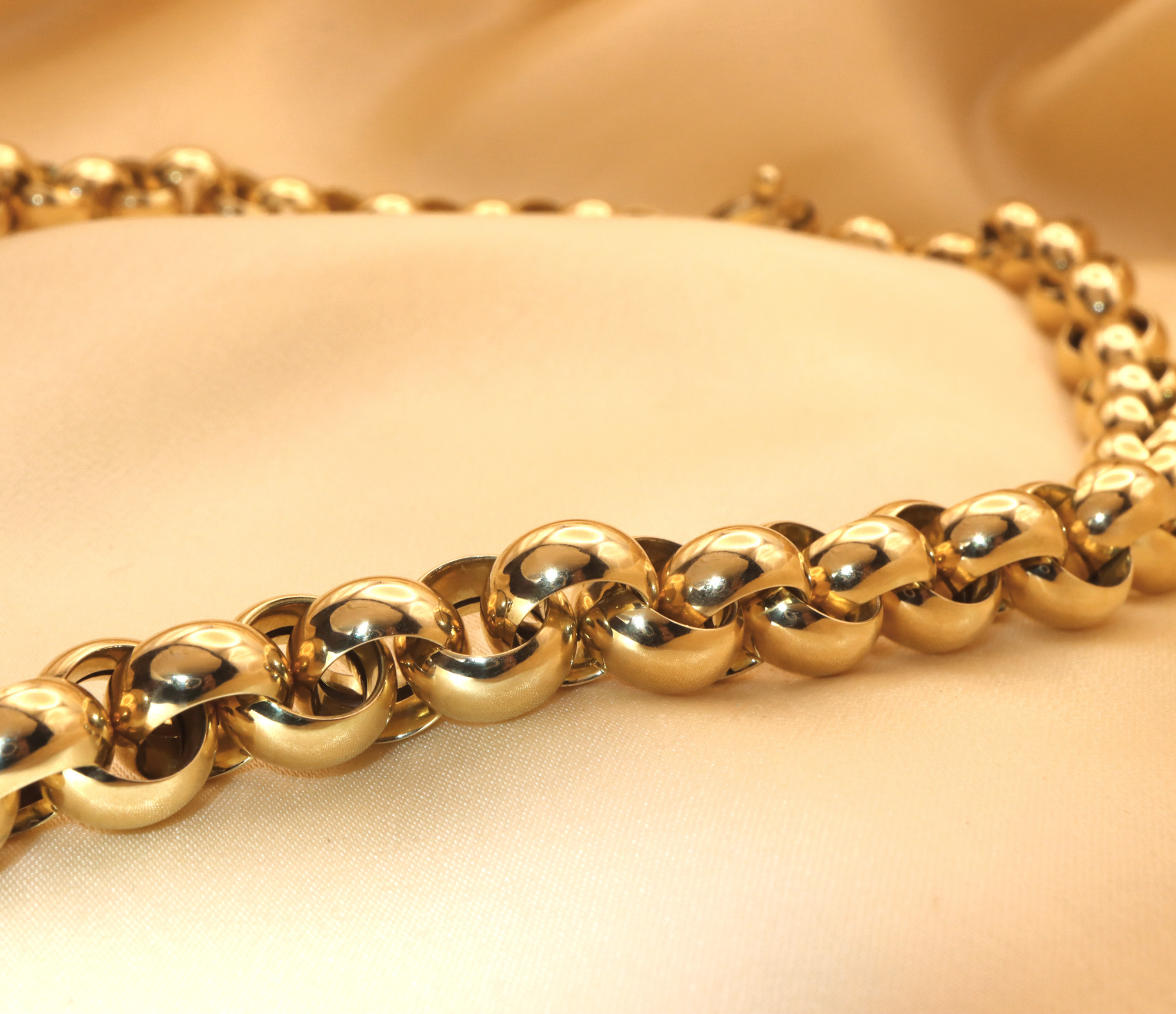 Goldene Halskette mit Ballkugeln auf cremefarbener Seide