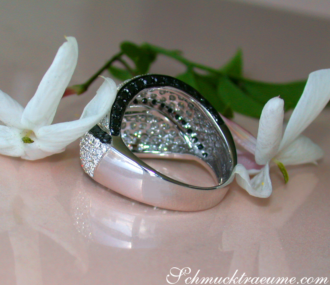 Schwarz-weißer Brillantenring mit Diamanten, Detailaufnahme auf weißem Hintergrund mit Blume.