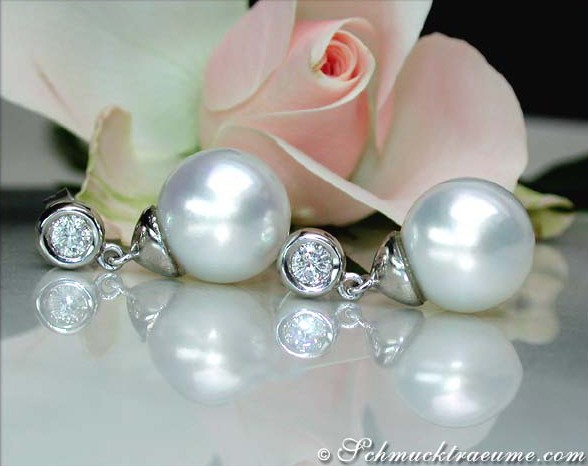 Weißgold-Ohrringe mit Perlen und Brillanten auf Rosenblütenhintergrund