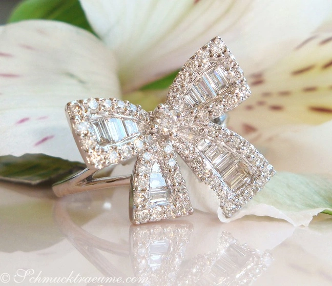 Femininer Diamanten-Schleifen-Ring in Weißgold, detailreich, auf Blüte präsentiert Femininer Diamanten-Schleifen-Ring in Weißgold, detailreich, auf Blüte präsentiert