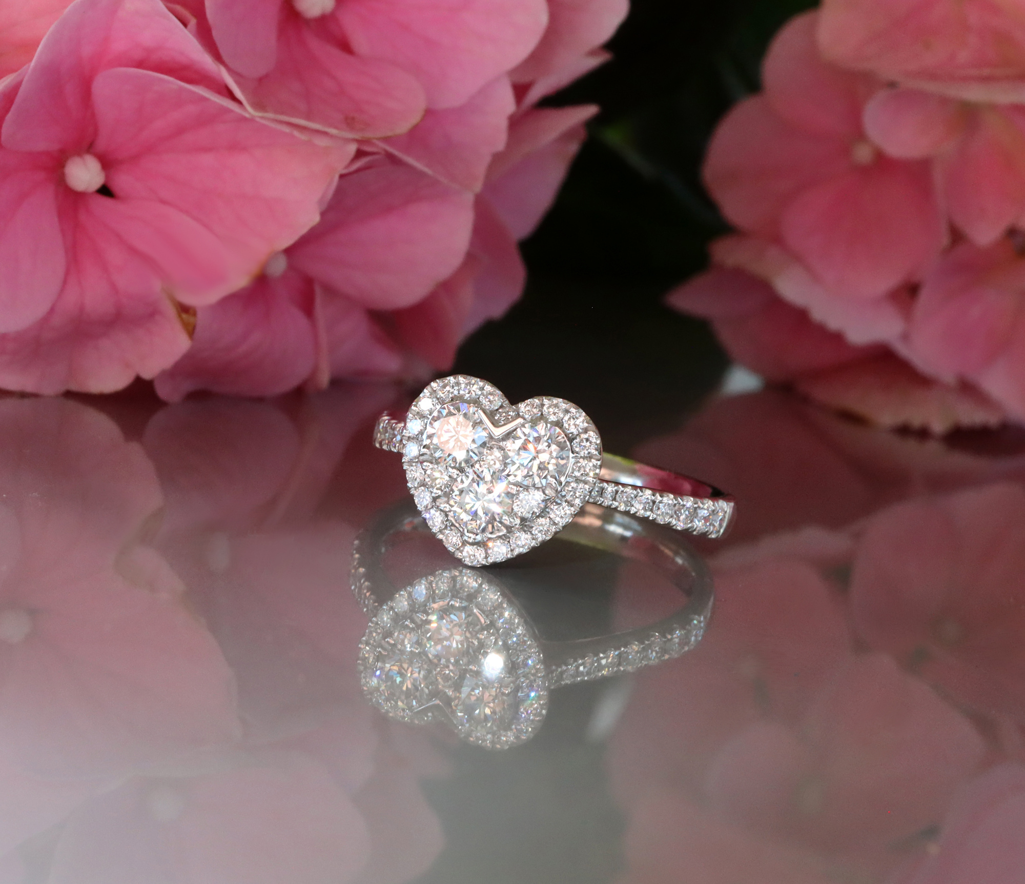Herzformiges Brillantenring-Detail vor rosa Blüten, Weißgold 750